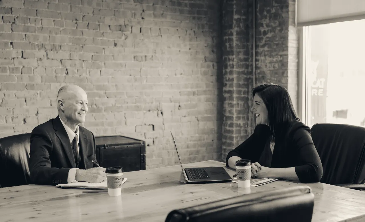 An owner and an advisor in conversation across a boardroom table